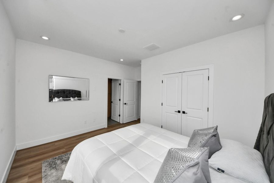Discover the inviting second-floor bedroom, featuring sleek hardwood floors, soothing white walls, and ample closet space, perfect for a cozy retreat.