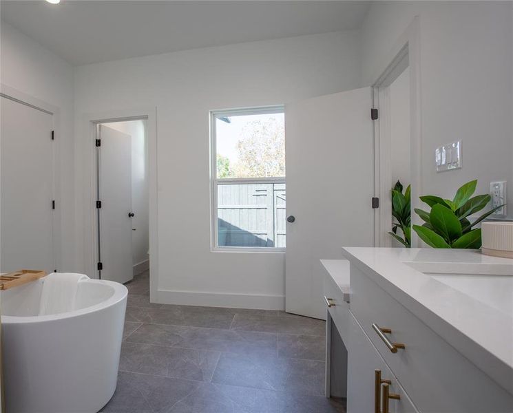 Bathroom with a washtub, vanity, and tile patterned flooring