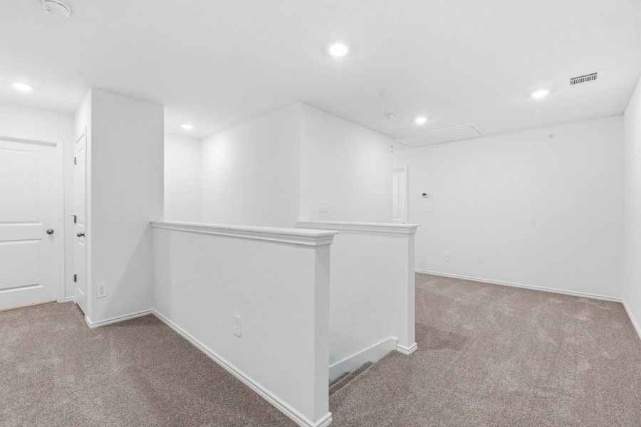 Spacious loft area featuring neutral carpeting, white painted walls, recessed lighting, and white trim Spacious loft area featuring neutral carpeting, white painted walls, recessed lighting, and white trim