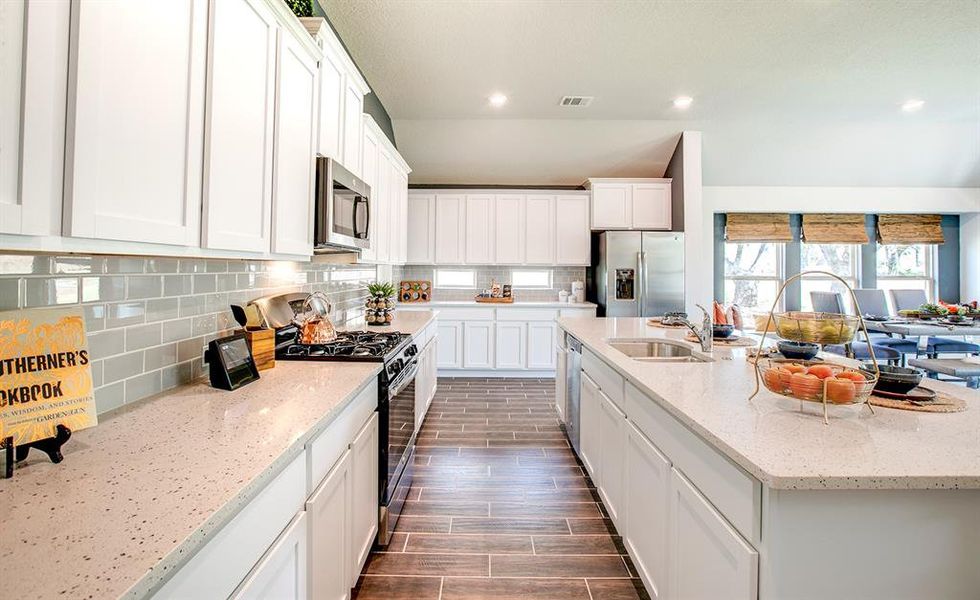 Kitchen featuring stainless steel appliances, tasteful backsplash, an island with sink, white cabinetry, and recessed lighting Kitchen featuring stainless steel appliances, tasteful backsplash, an island with sink, white cabinetry, and recessed lighting