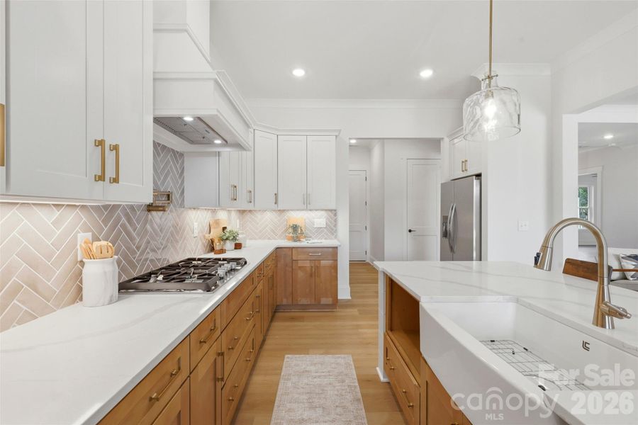 gourmet kitchen- custom  wood hood vent, porcelain farmmhouse sink, high quality quartz island, double oven, gas cooktop