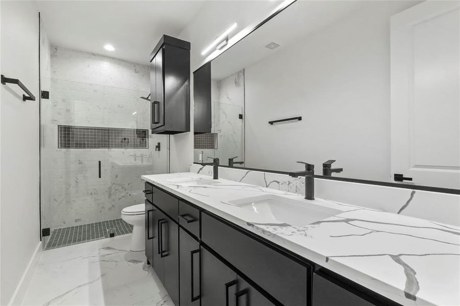 Bathroom with a marble finish shower, light marble finish floors, double vanity, and recessed lighting Bathroom with a marble finish shower, light marble finish floors, double vanity, and recessed lighting