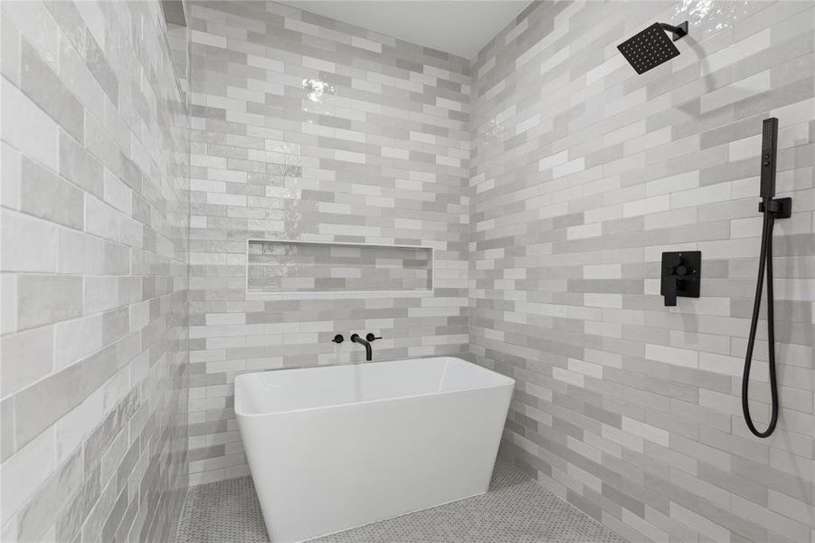 Freestanding soaking tub set against a tiled wall with a recessed niche Freestanding soaking tub set against a tiled wall with a recessed niche