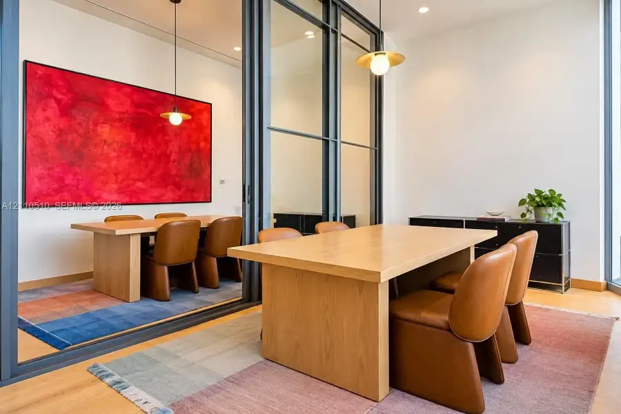 Floor-to-ceiling glass sliding partition with dark metal framing, recessed lighting, and suspended metallic pendant fixtures featuring spherical bulbs Floor-to-ceiling glass sliding partition with dark metal framing, recessed lighting, and suspended metallic pendant fixtures featuring spherical bulbs