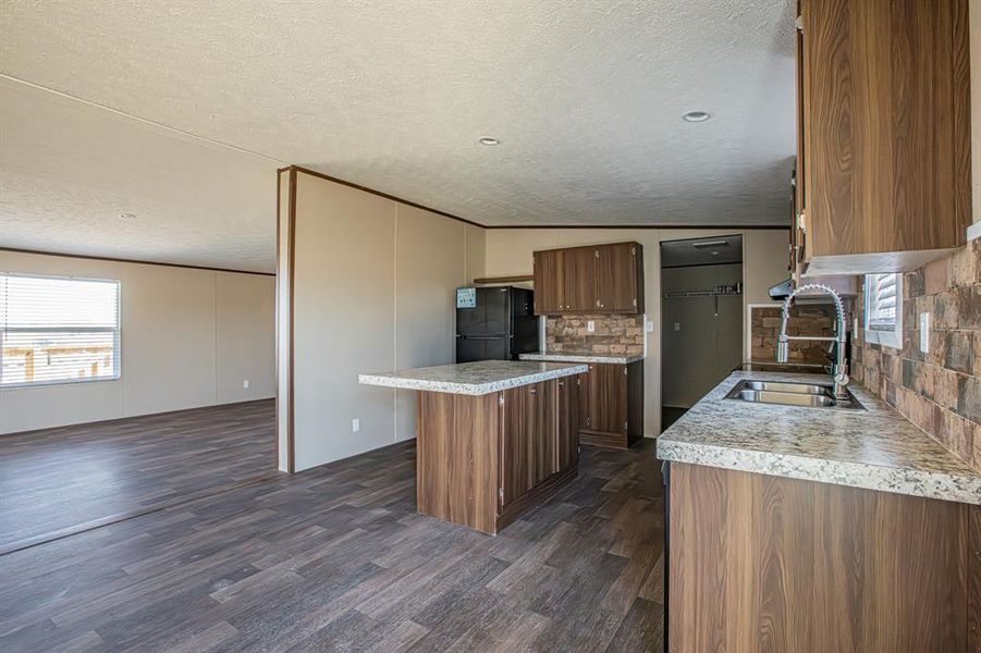 Kitchen featuring a center island, black fridge, decorative backsplash, and sink