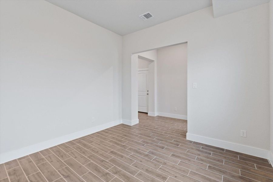 Natural light illuminates this versatile living space, featuring wood-look tile flooring.