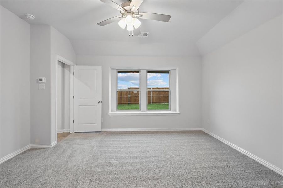 Unfurnished room with light colored carpet, lofted ceiling, and a ceiling fan