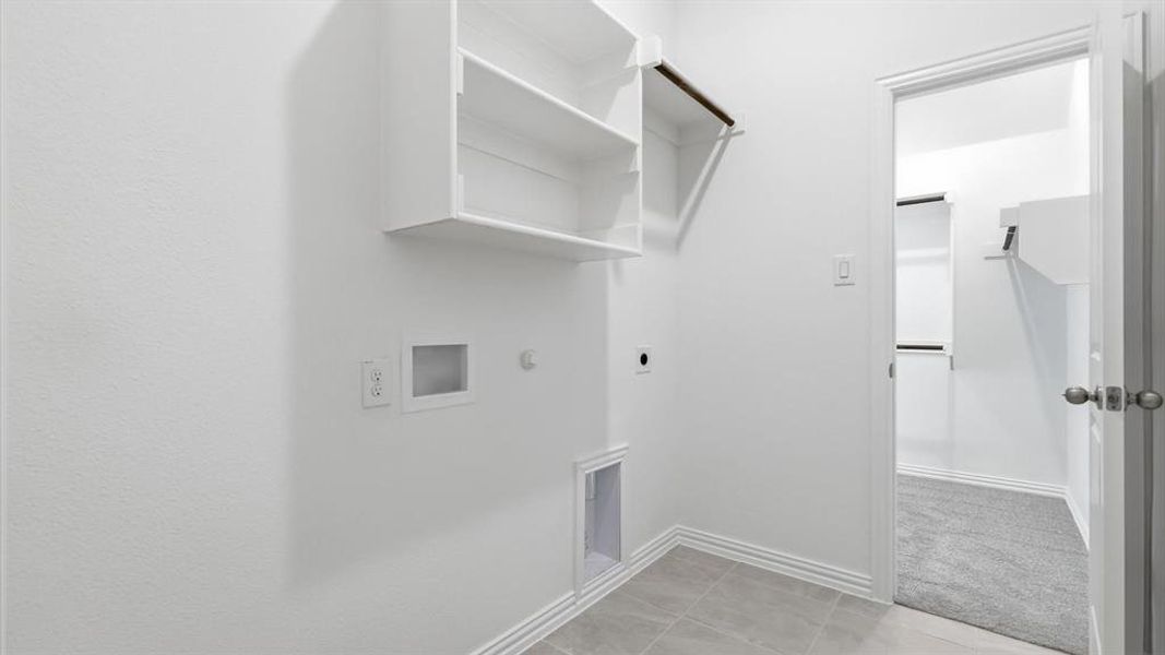Laundry area featuring built-in shelving, a clothes hanging rod, tile flooring, and white baseboards