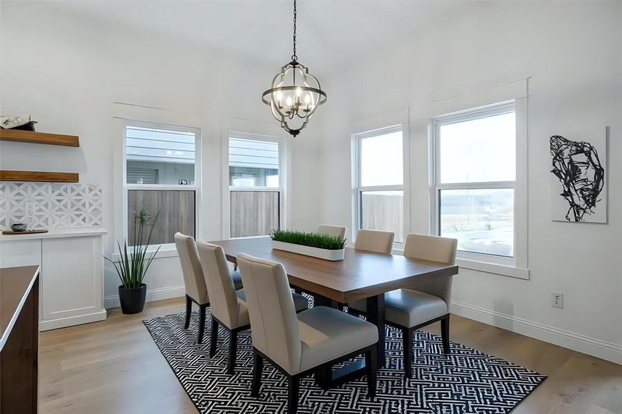 Dining room with light wood finished floors, plenty of natural light, and a chandelier