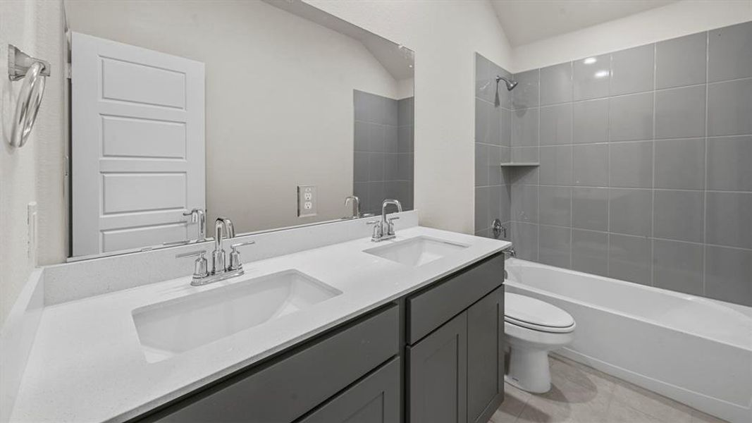Bathroom featuring a dual vanity with white countertops, chrome fixtures, and gray cabinetry
