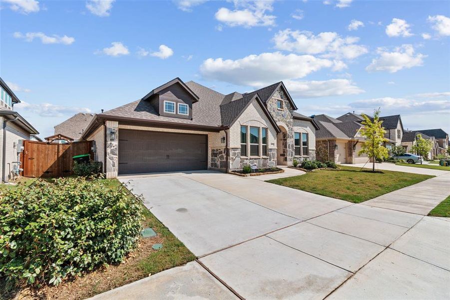 French country home featuring stone siding, concrete driveway, a shingled roof, and a residential view