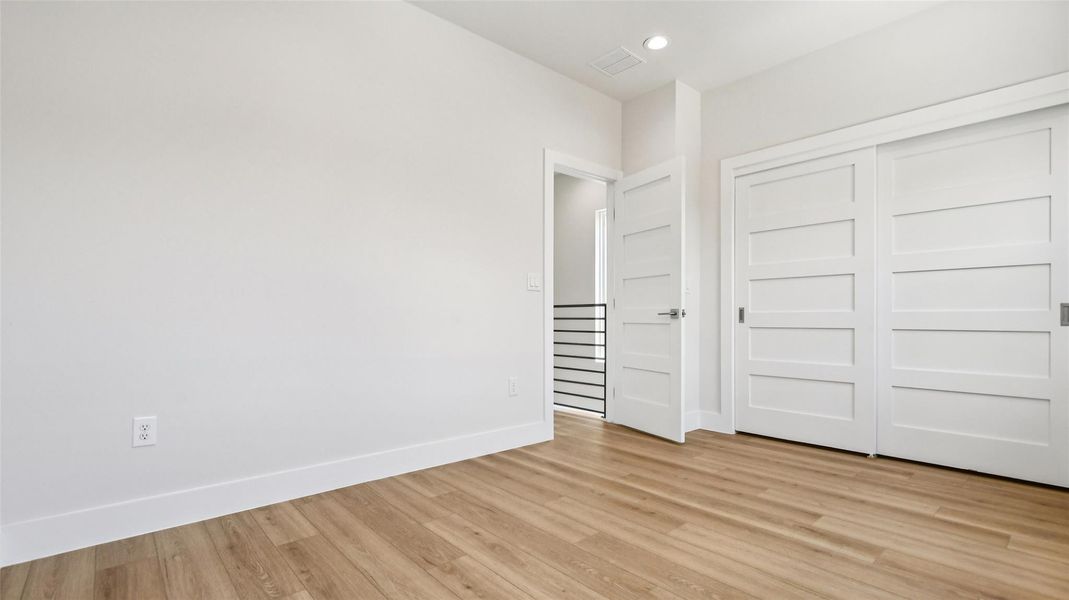 Unfurnished bedroom with light wood finished floors, a closet, and recessed lighting Unfurnished bedroom with light wood finished floors, a closet, and recessed lighting