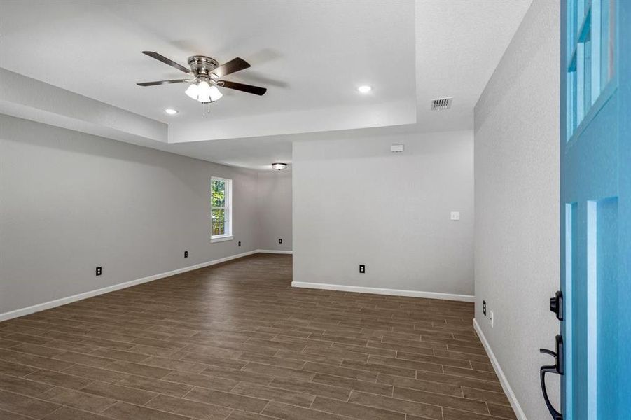 Unfurnished room featuring a tray ceiling, recessed lighting, wood tiled floors, and a ceiling fan Unfurnished room featuring a tray ceiling, recessed lighting, wood tiled floors, and a ceiling fan