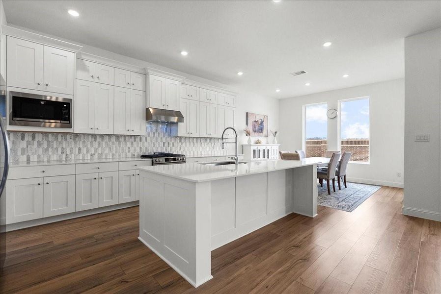 The chef’s eat-in island kitchen is the heart of the home, featuring lengthy quartz countertops, an abundance of upgraded cabinetry with crown molding, a designer backsplash, and stainless steel appliances. The chef’s eat-in island kitchen is the heart of the home, featuring lengthy quartz countertops, an abundance of upgraded cabinetry with crown molding, a designer backsplash, and stainless steel appliances.