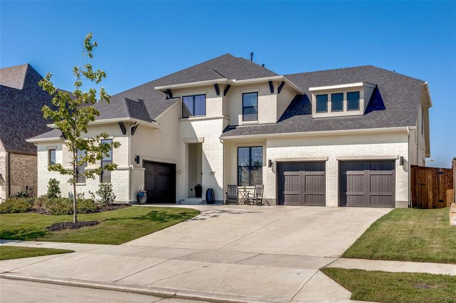 View of front facade with concrete driveway, a garage, a front yard, a shingled roof, and brick siding View of front facade with concrete driveway, a garage, a front yard, a shingled roof, and brick siding