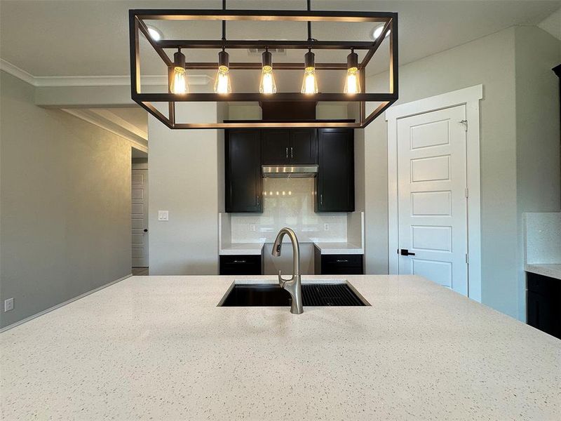 Kitchen island featuring a spacious light-toned countertop with an undermount sink and a gooseneck faucet