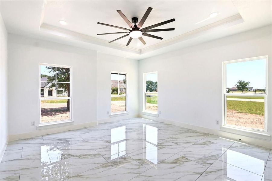 Spacious interior room featuring polished large-format tile flooring, a tray ceiling with recessed lighting, and a contemporary ceiling fan