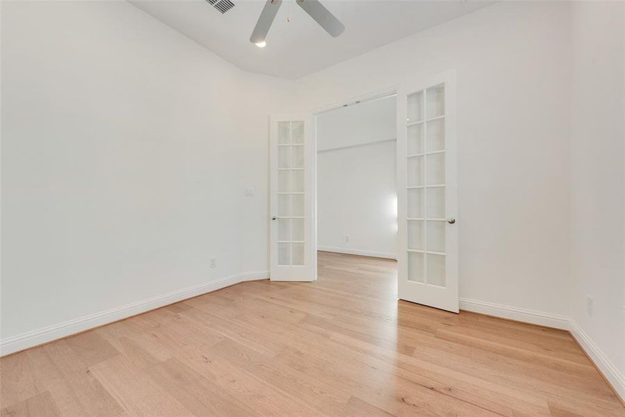 Spare room featuring ceiling fan, french doors, and light hardwood / wood-style floors