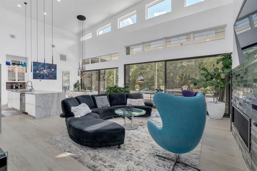 Living area featuring light wood-style flooring, a towering ceiling, and recessed lighting