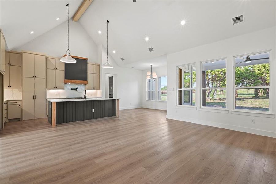 Kitchen featuring beamed ceiling, a center island with sink, open floor plan, high vaulted ceiling, and decorative light fixtures Kitchen featuring beamed ceiling, a center island with sink, open floor plan, high vaulted ceiling, and decorative light fixtures