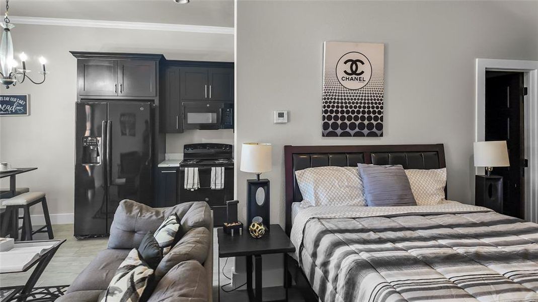 Bedroom with black refrigerator with ice dispenser, light wood-style flooring, crown molding, and a chandelier