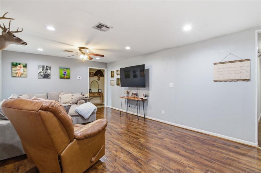 Spacious interior featuring wood-finish flooring, light grey painted walls, recessed lighting, and a ceiling fan