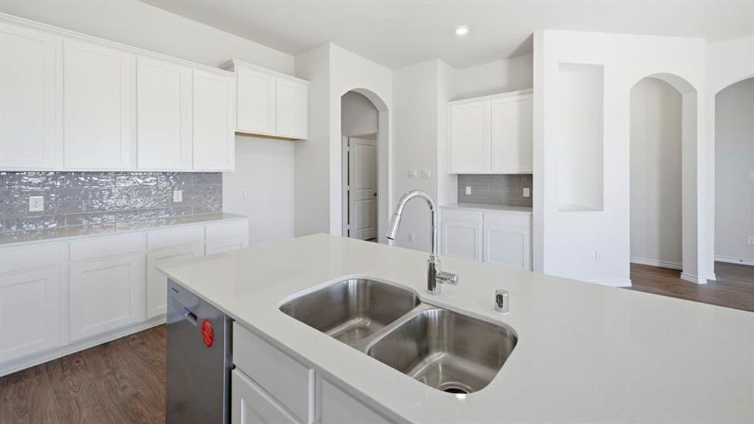 Kitchen with white cabinetry, dark wood-style floors, arched walkways, decorative backsplash, and recessed lighting