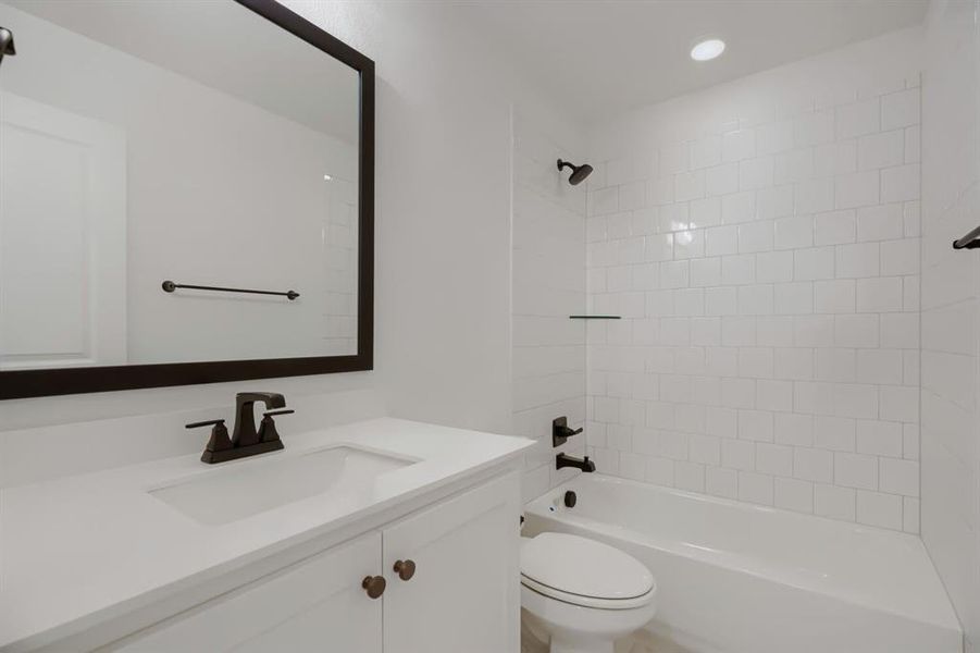 Bright bathroom featuring a white vanity with integrated sink, a dark-framed mirror, and matte black fixtures Bright bathroom featuring a white vanity with integrated sink, a dark-framed mirror, and matte black fixtures