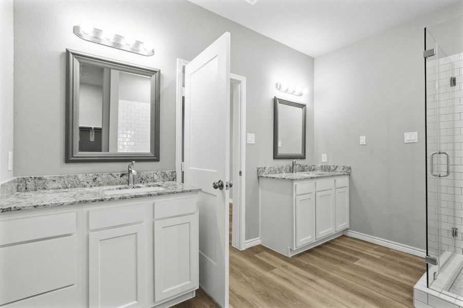 Primary bathroom offering his and her sinks and vanity area.