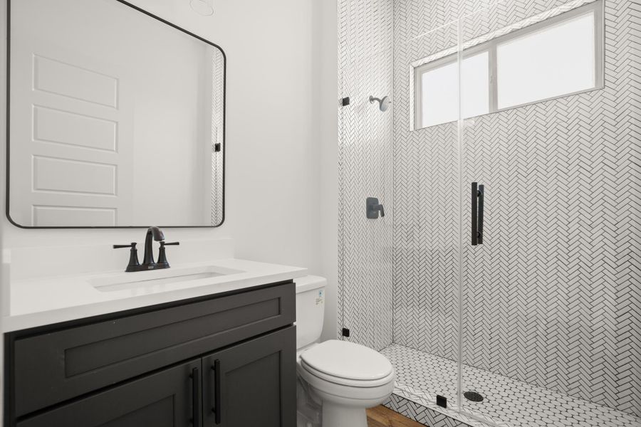 A sleek vanity with a dark cabinet and white countertop anchors this modern bathroom, complemented by a herringbone-tiled shower. A sleek vanity with a dark cabinet and white countertop anchors this modern bathroom, complemented by a herringbone-tiled shower.