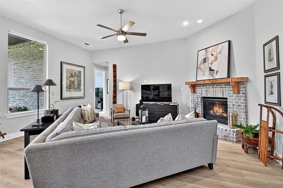 Living room with a ceiling fan, a brick fireplace, light wood-type flooring, and recessed lighting Living room with a ceiling fan, a brick fireplace, light wood-type flooring, and recessed lighting