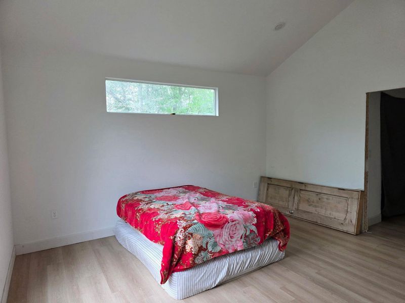 This room features light-toned flooring, white walls, and a high, sloped ceiling