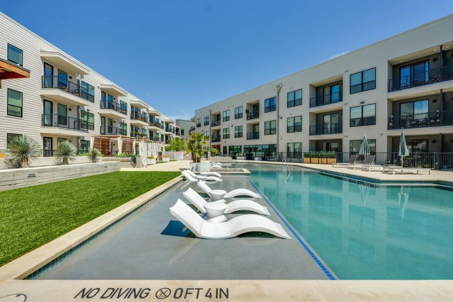 The property features a large swimming pool with in-pool loungers, surrounded by landscaped turf areas and paved walkways