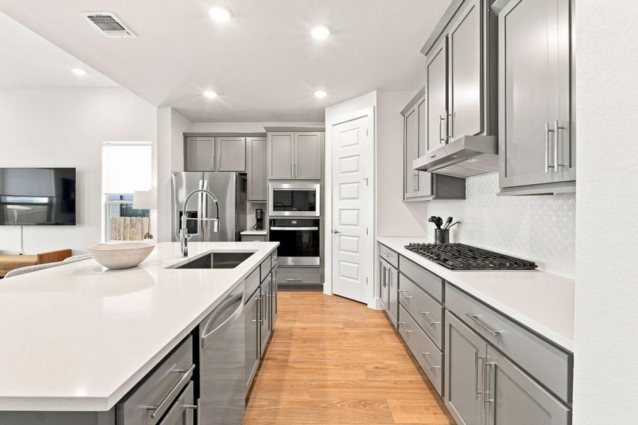 Chef’s kitchen equipped with 3 CM Ariel Silestone counters, 36" Whirlpool gas cooktop, white quadrangle tile backsplash, and stainless range hood. Chef’s kitchen equipped with 3 CM Ariel Silestone counters, 36" Whirlpool gas cooktop, white quadrangle tile backsplash, and stainless range hood.