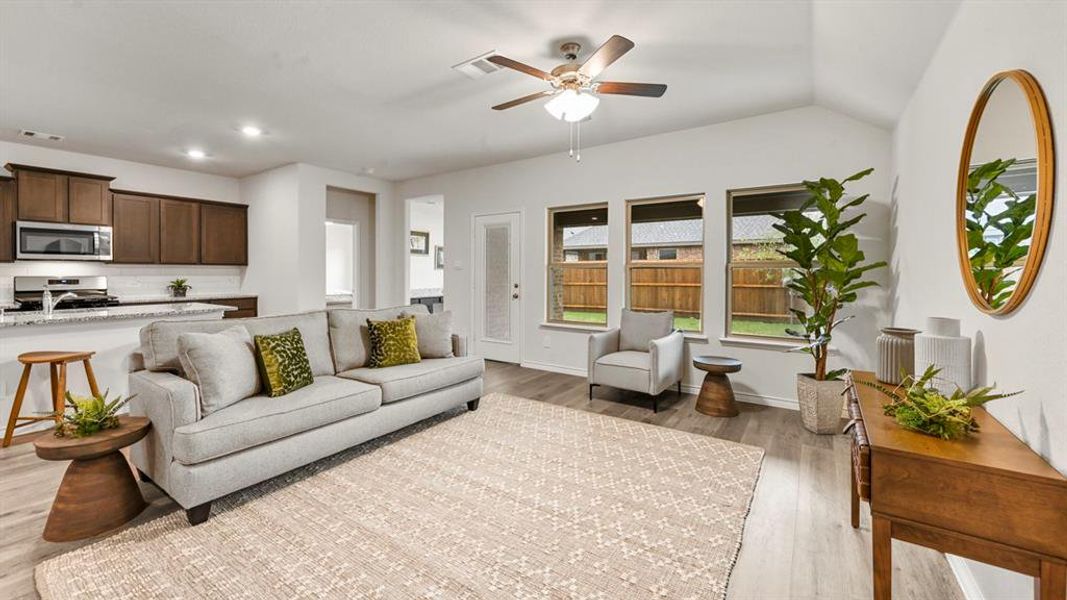Living room with a ceiling fan, light wood-style floors, and lofted ceiling