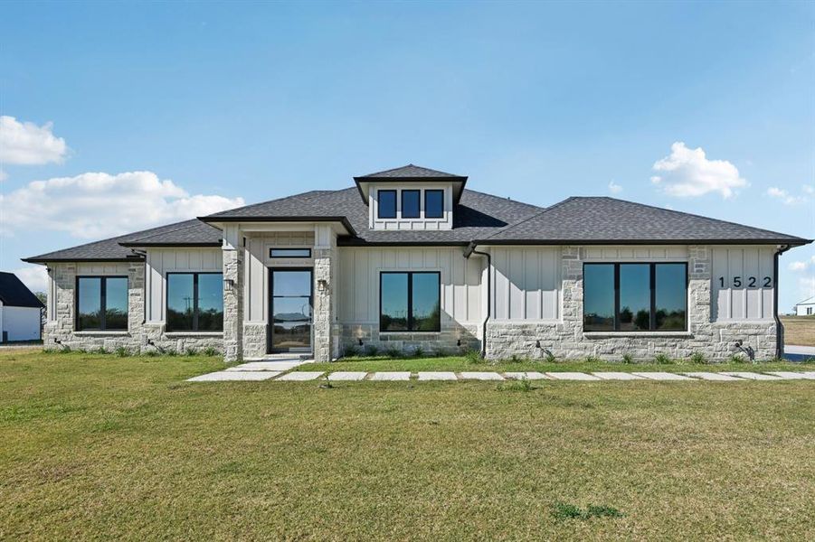 View of front of house featuring stone siding, a front yard, and a shingled roof View of front of house featuring stone siding, a front yard, and a shingled roof