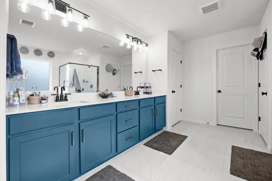 Double vanity featuring blue cabinetry with brushed nickel hardware, white countertop, dual undermount sinks, and matte black faucets
