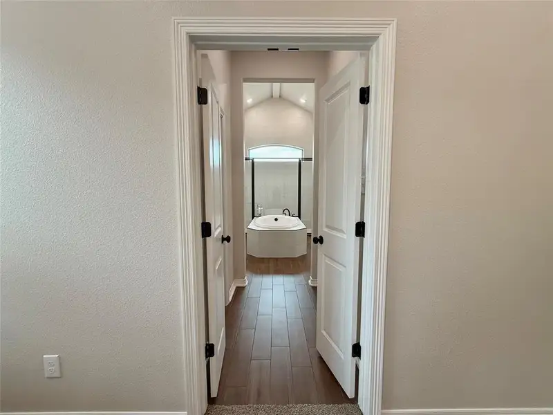 Hall featuring dark wood-type flooring, lofted ceiling, and a textured wall Hall featuring dark wood-type flooring, lofted ceiling, and a textured wall