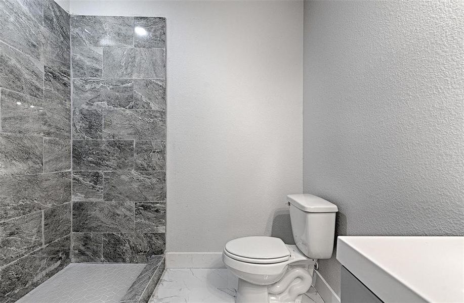 Bathroom with vanity, toilet, and tiled shower