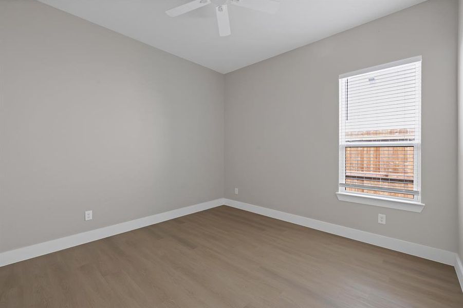 Spare room featuring baseboards, wood finished floors, and a ceiling fan