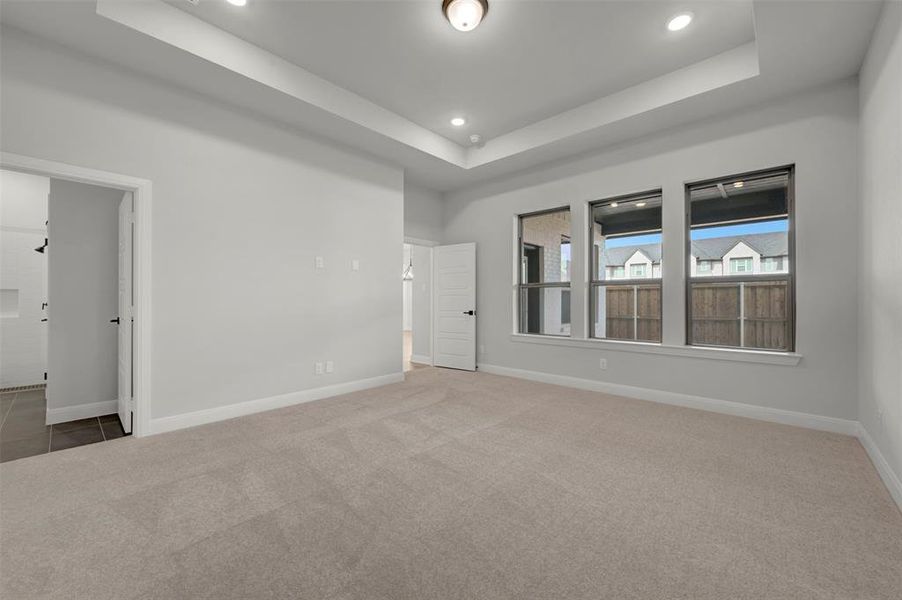 Unfurnished room with light carpet, a tray ceiling, and recessed lighting
