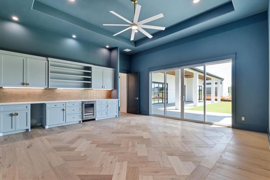 Unfurnished office with beverage cooler, a raised ceiling, ceiling fan, a high ceiling, and recessed lighting