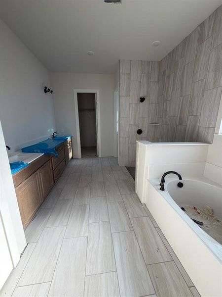Bathroom with a garden tub, a spacious closet, a walk in shower, and double vanity