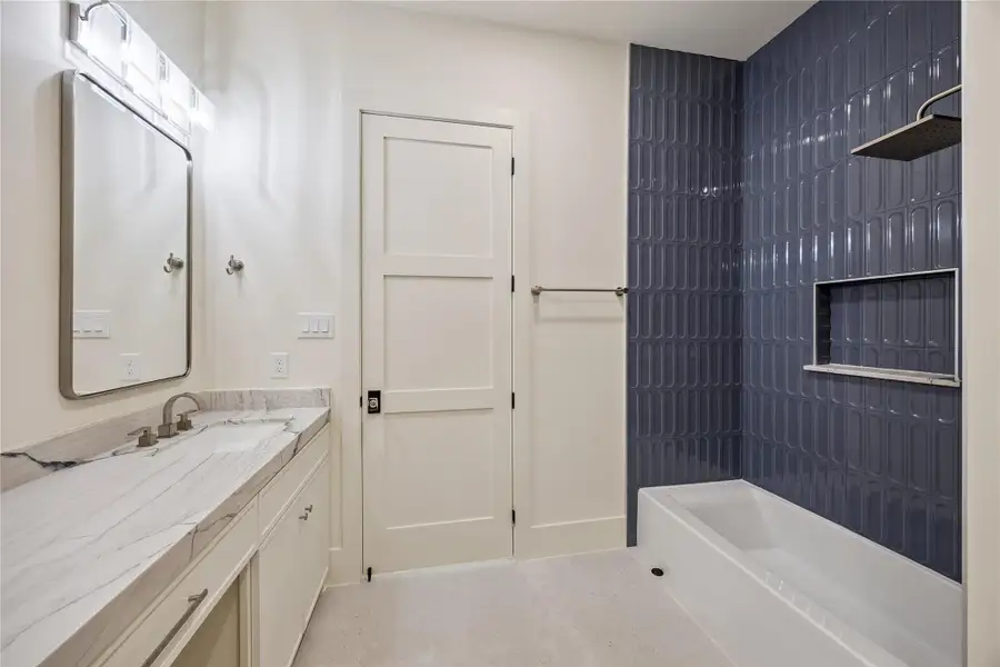 SECONDARY BATH: Stylish secondary bath features Mont Blanc Gold Quartzite countertops, decorative blue porcelain surround, and a tub/shower combination.