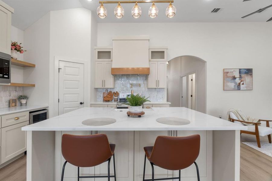 Kitchen featuring light stone countertops, open shelves, and light wood-style flooring Kitchen featuring light stone countertops, open shelves, and light wood-style flooring