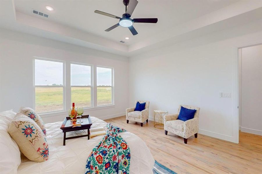 Sitting room with ceiling fan, a tray ceiling, and light hardwood / wood-style floors