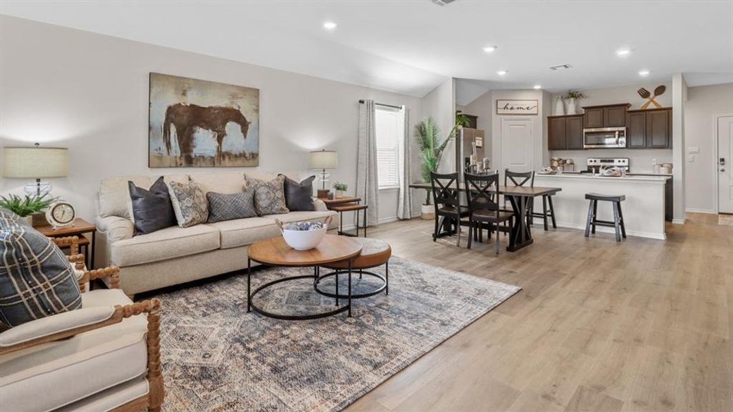 Spacious open-concept living area featuring light wood-finish flooring, recessed lighting, and a neutral color palette