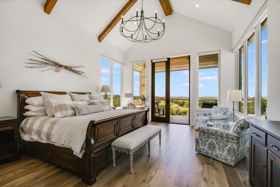 Bedroom with beamed ceiling, access to exterior, a chandelier, wood finished floors, and high vaulted ceiling Bedroom with beamed ceiling, access to exterior, a chandelier, wood finished floors, and high vaulted ceiling