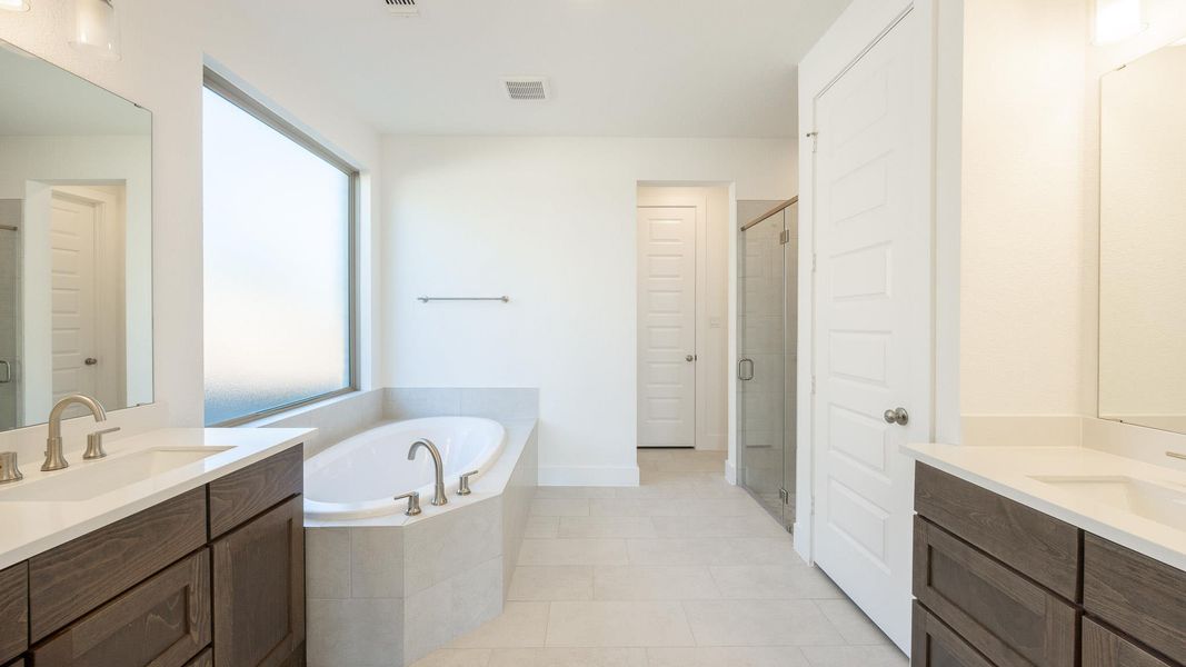 Full bath with two vanities, tile patterned floors, a sink, a shower stall, and a bath