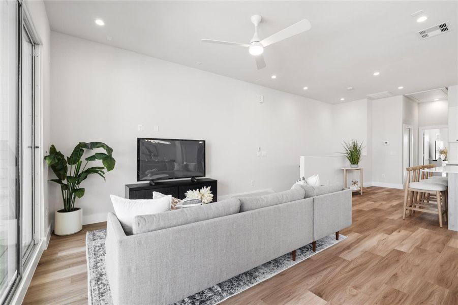 This angle highlights the seamless flow between the living area and kitchen, anchored by a central island that keeps everything connected. The layout is open without feeling exposed, making it easy to entertain, cook, and relax without breaking the rhythm of the space.